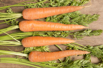 Selection of fresh raw carrots on a wooden kitchen work surface
