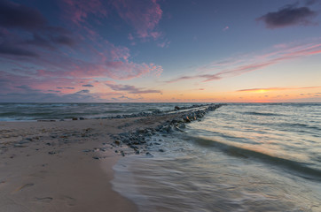 Baltic sea coast at sunset, with groyne made of granite stones in Rowy, near Ustka, Poland