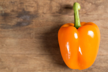 Fresh raw orange pepper on wooden kitchen work surface
