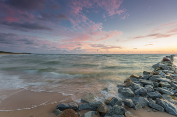 Baltic sea coast at sunset, with groyne made of granite stones in Rowy, near Ustka, Poland