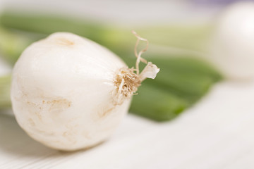 Large spring onion bulbs on a light wooden surface