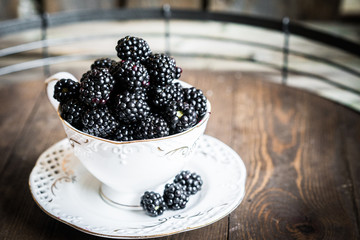 Blackberries in a mug on wooden background