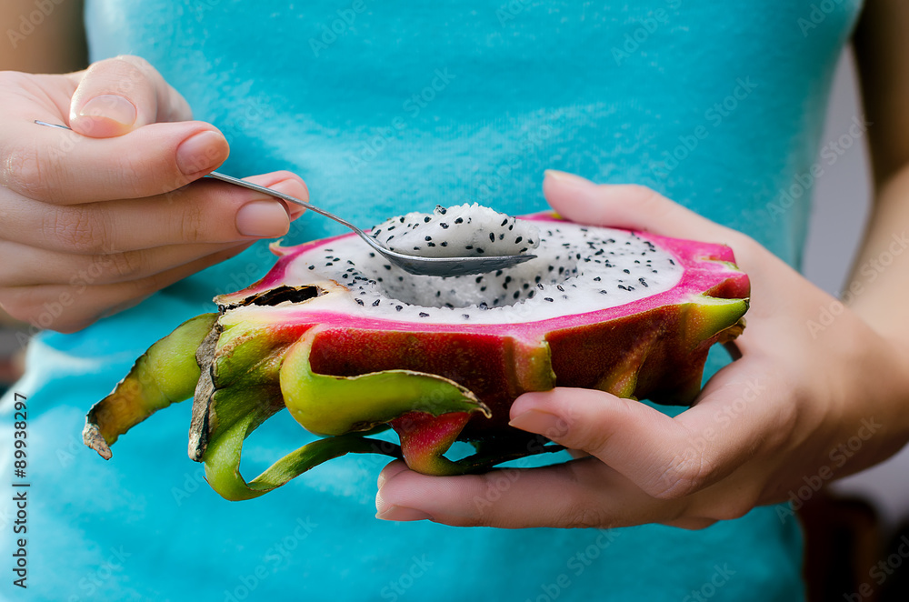 Wall mural half dragon fruit in female hands.