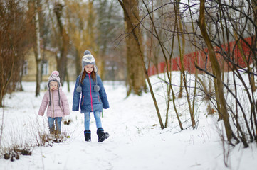 Fototapeta na wymiar Two funny adorable little sisters winter park