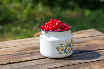 Cherries in white metal cans on a wooden table