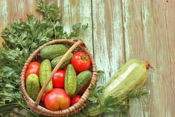 Basket with cucumbers, tomatoes, parsley, zucchini on wooden background