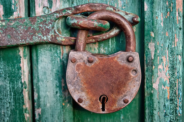 On the old wooden door, installed a rusty padlock