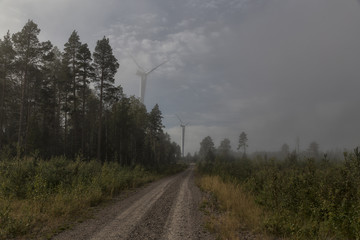 Fototapeta premium Two turbines on a road with foggy conditions