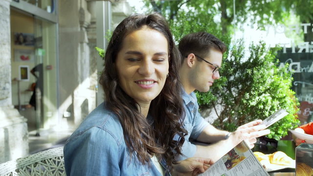 Friends looking to the camera in the outdoor cafe, steadycam shot
