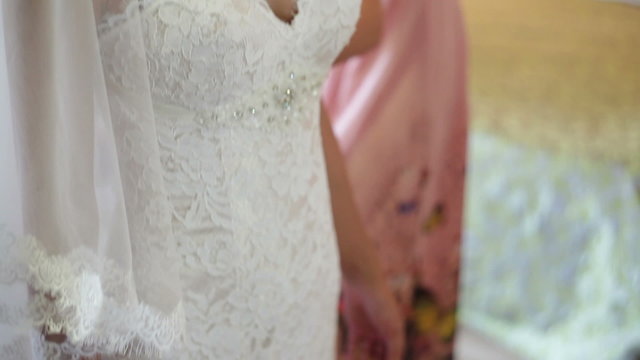 Bride trying on wedding dress before the mirror
