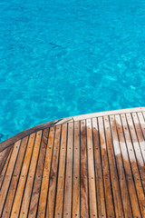 Fototapeta na wymiar In the pictured curved wooden deck wet and in the background ocean blue / turquoise.