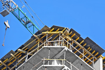 Crane and building construction site against blue sky