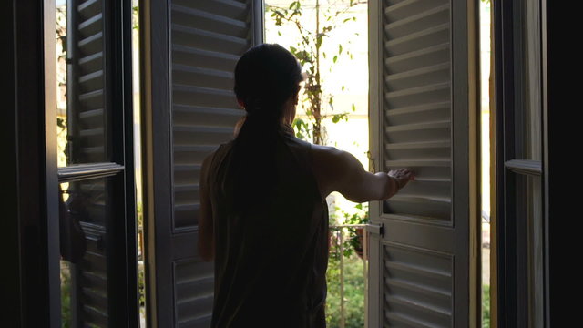 Woman going inside and closing patio doors, steadycam shot
