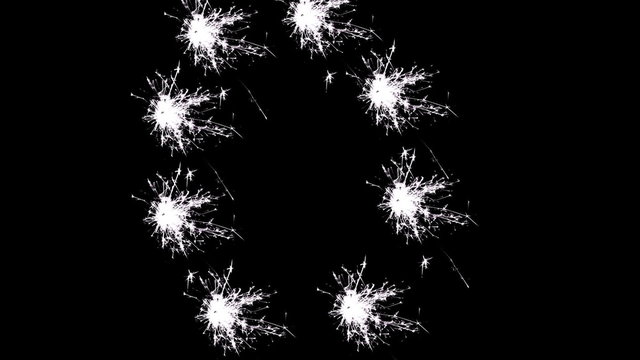 Capital letter O spelled with white sparklers on black background.