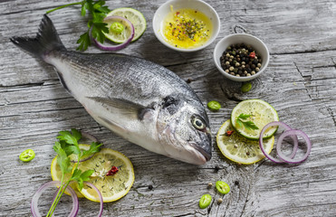 fresh Dorado fish, lemon, lime and parsley on a light wooden surface