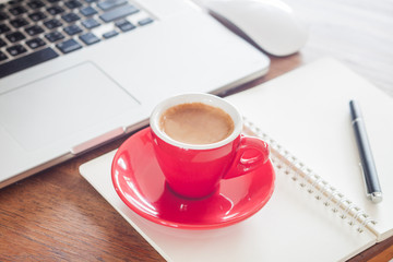 Red coffee cup with notepad and laptop