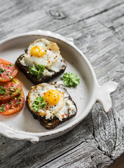 toast with feta cheese and fried quail egg, fresh tomatoes on a light wooden surface - a healthy Breakfast or snack