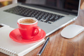 Red coffee cup with notepad and laptop
