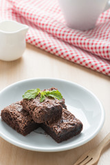 Pile of brownies on white dish.
