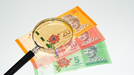 Magnifier with Malaysia bank notes.concept photo.