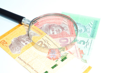 Magnifier with Malaysia bank notes.concept photo.
