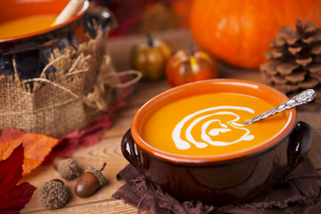 Homemade pumpkin soup on a rustic table with autumn decorations