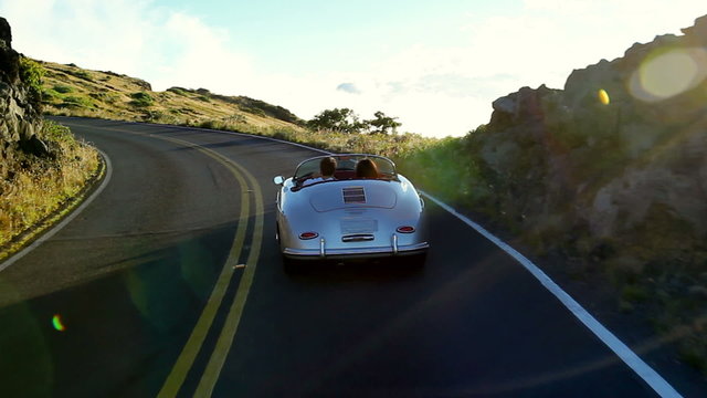 Happy Couple Driving Classic Convertible Car into Sunset on Country Road. Romantic Freedom Relaxing Road Trip Concept.