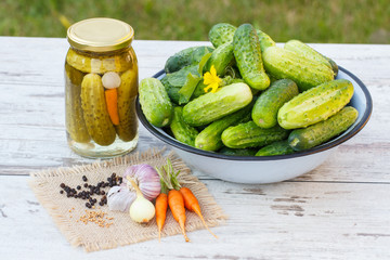 Cucumbers in metal bowl, vegetables and spices for pickling and jar pickled cucumbers