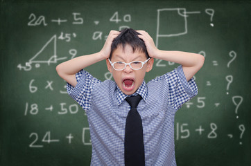 Asian schoolboy holding clock and screaming over chalkboard