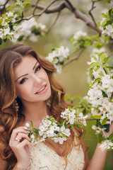 Young beautiful brunette woman in blooming garden