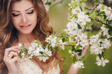 Fototapeta premium Young beautiful brunette woman in blooming garden