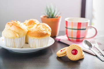 Sandwich cookies with cream and strawberry flavoured jam on wood
