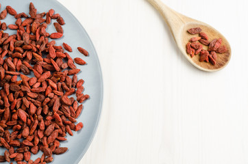 Goji berry dried in a dish, with spoon, closeup background