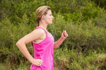 Pretty blonde athlete jogging and listening to music