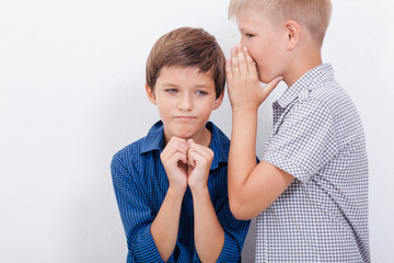 Teenage boy whispering in the ear a secret to friendl on white