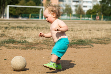 baby learning to play football at the stadium