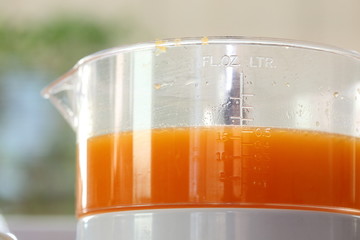 fresh orange juice in juicer machine with hand