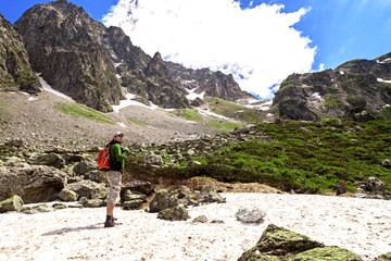 Man hiking in the mountains on a tourist track near a lake