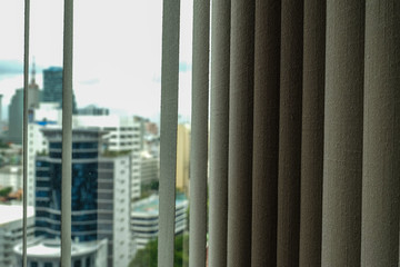 Grey curtain in a dark room on blurred city view