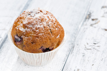 muffin with raisins and icing sugar on white wooden background