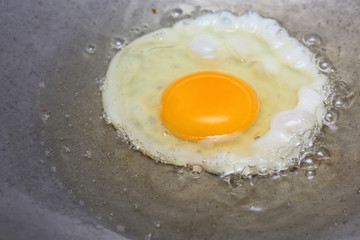 cooking fried egg in hot pan with oil