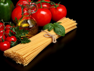 Pasta raw isolated on black with tomatoes,olive oil,garlic
