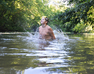 Fototapeta na wymiar Boy teenager swims in river in summer