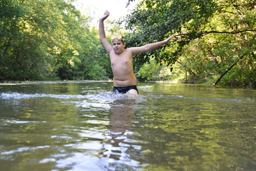 Boy teenager swims in  river in summer