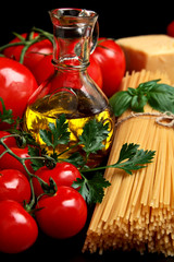 Pasta raw isolated on black with tomatoes,olive oil,garlic verti