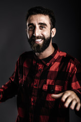 Portrait of a happy young man with beard, dancing against gray b