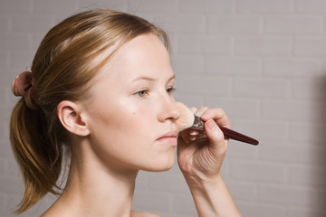 Fototapeta premium Beautiful blond model applying blusher on cheeks