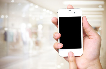 Hand holding smart phone over blur store background, business an