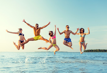 smiling friends in sunglasses on summer beach