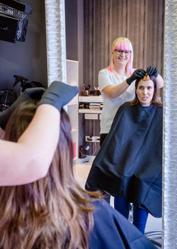 Woman With Hairdresser Looking Hair Dye Sample In Mirror